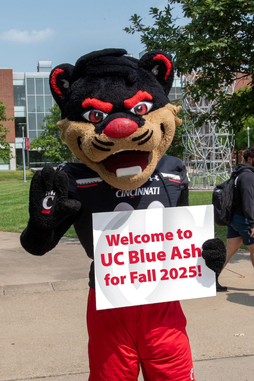 bearcat mascot holding a Welcome to on UC Blue Ash campus sign