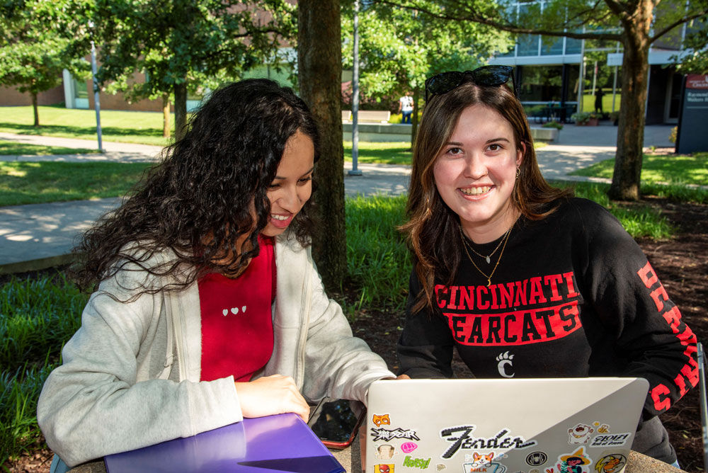 two female students working outside on the UC Blue Ash campus