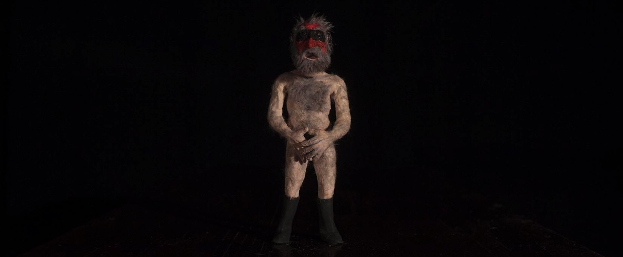 Photograph of figure standing with a black background