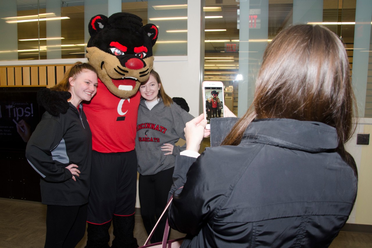 Two students getting their photo taken with the UC bearcat