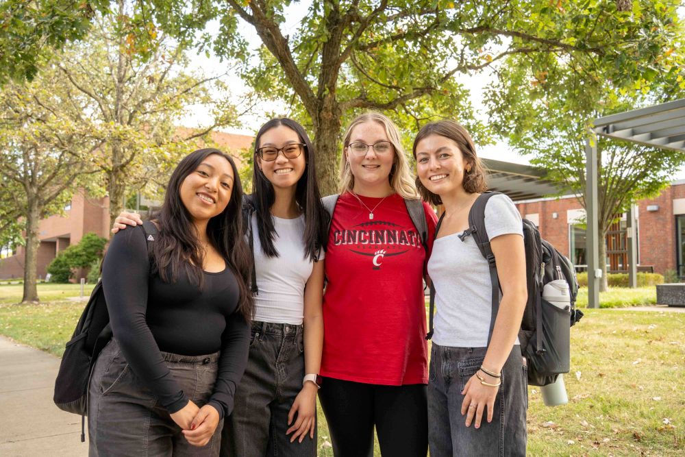 four female students standing together outside on the UC Blue Ash campus