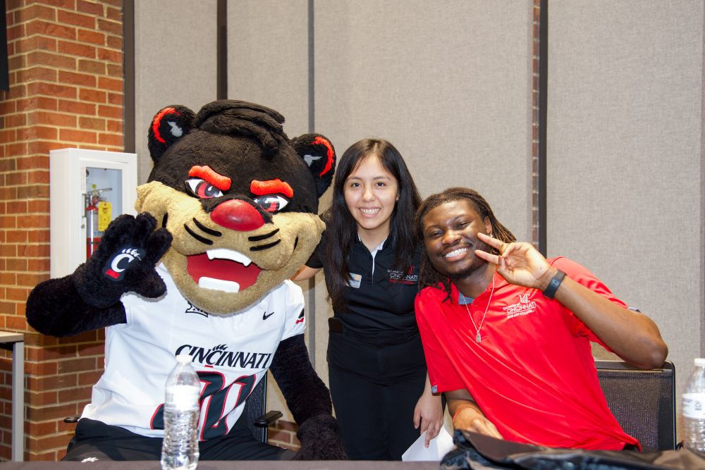 two student ambassadors celebrating success on campus with bearcat mascot