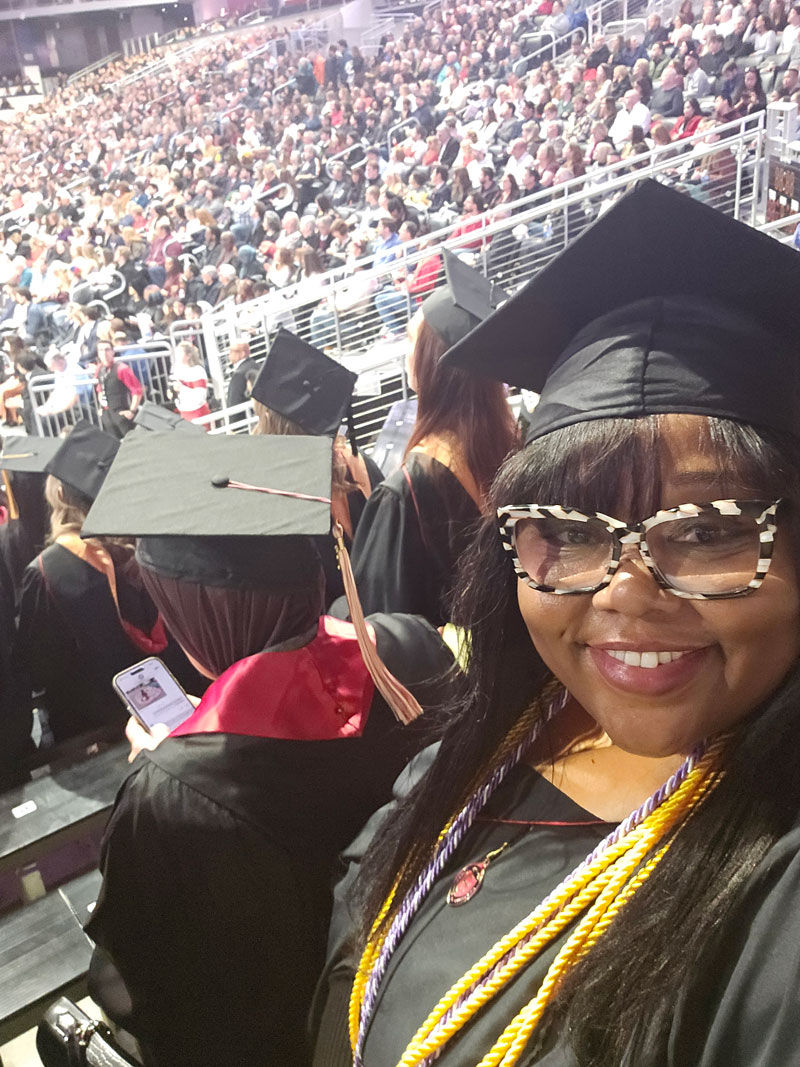 woman taking selfie in cap and gown at commencement