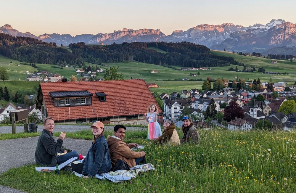 a field of people enjoying a picnic outside near the Swiss Alps