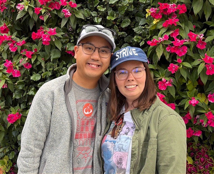 Joe Tran and his wife in front of flowers
