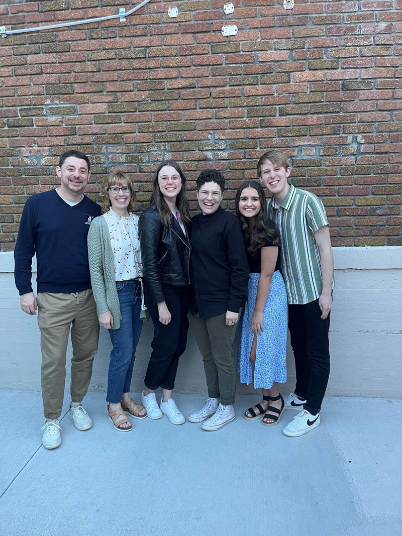 family of six posing in front of brick wall
