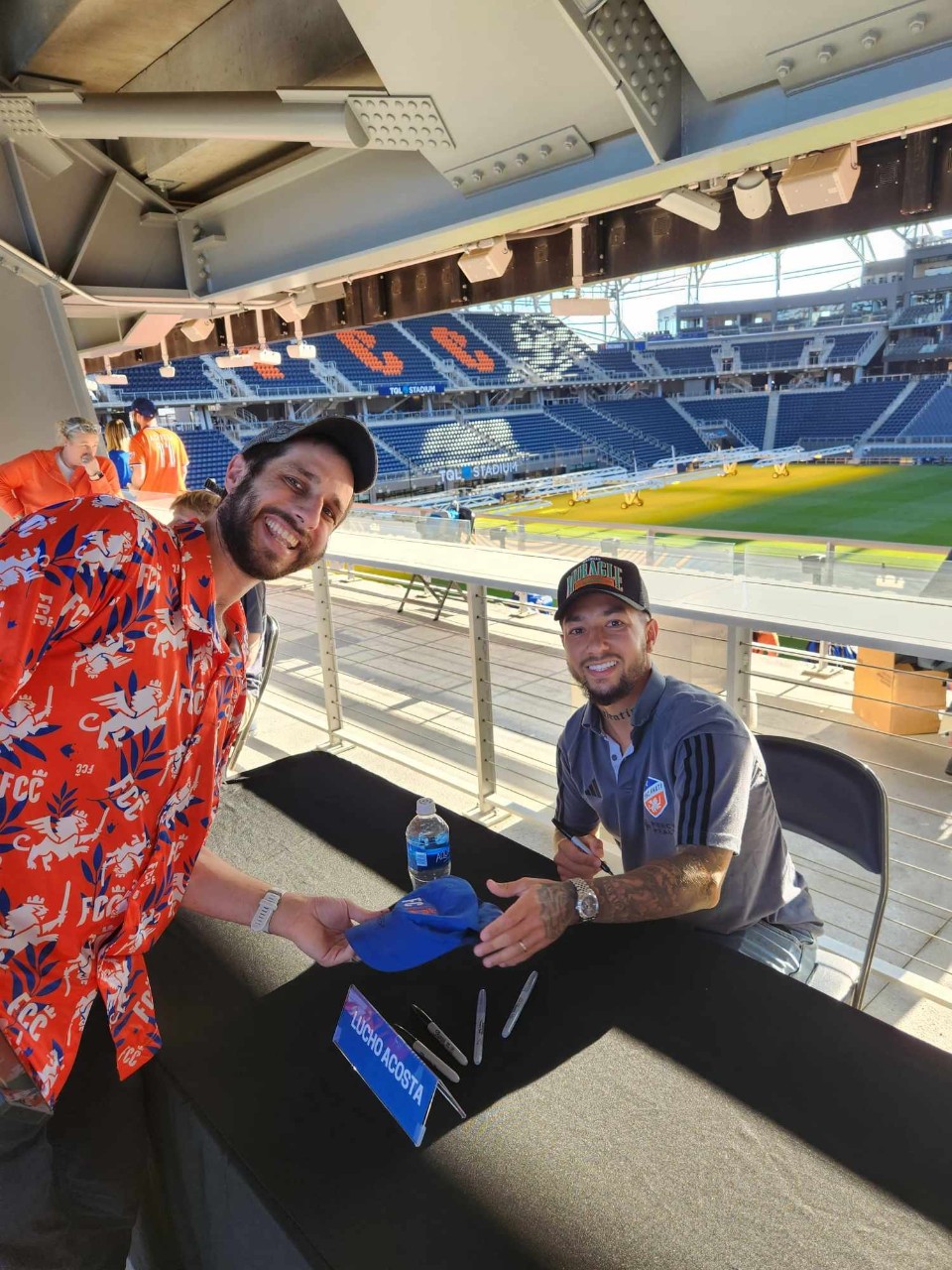 two men smiling for camera at stadium