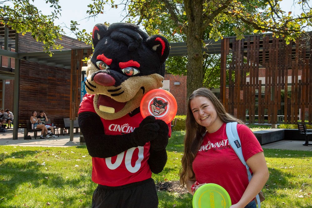 Student and bearcat mascot enjoying outside patio Muntz Hall at UC Blue Ash College