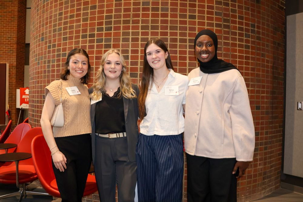 group of four female students smiling in the Muntz Hall Atrium
