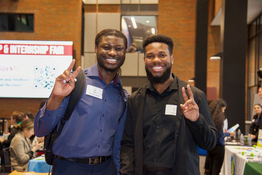 Two smiling male students at the UC Blue Ash career fair